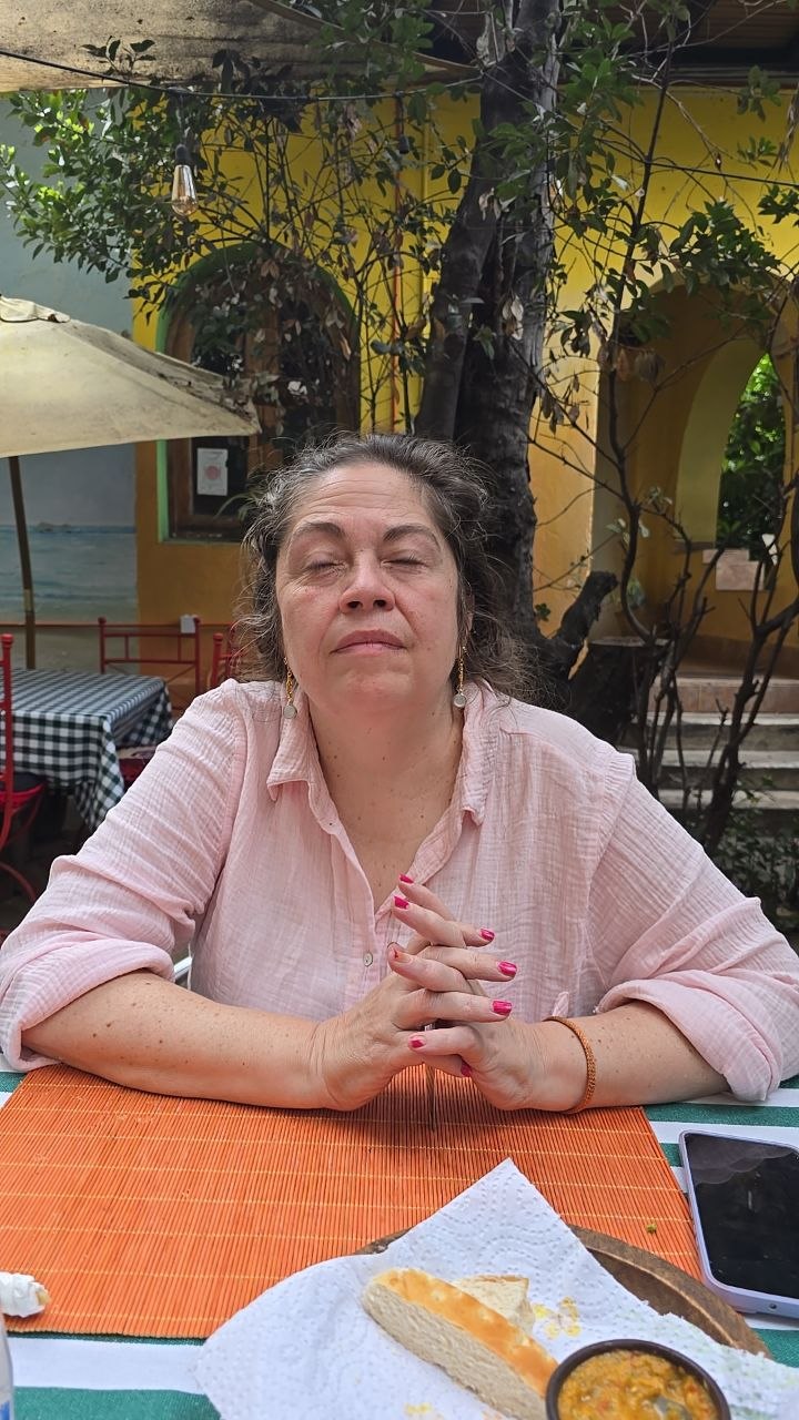 Sofía Vera sentada al aire libre, con los ojos cerrados y las manos entrelazadas, en un momento de reflexión